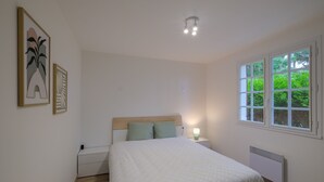 A bedroom with a bed, bedside table, nightstand, and a window with a view of greenery. - Villa Bihen - Maison vue mer, Pénestin (Pénestin)