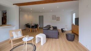 A modern living room with a sofa, ottoman, coffee table, and a dining area with chairs and a table. - Villa Bihen - Maison vue mer, Pénestin (Pénestin)