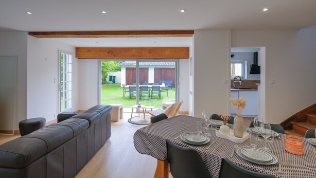 A modern dining area with a long table set for six, a built-in bench, and a view of the backyard. - Villa Bihen - Maison vue mer, Pénestin (Pénestin)