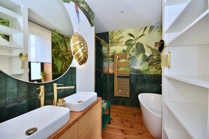 Une salle de bain moderne avec deux lavabos, un grand miroir et une baignoire.