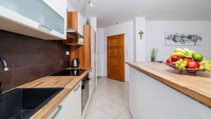 Una cocina moderna con un lavamanos negro, encimera de madera y un frutero en la isla.