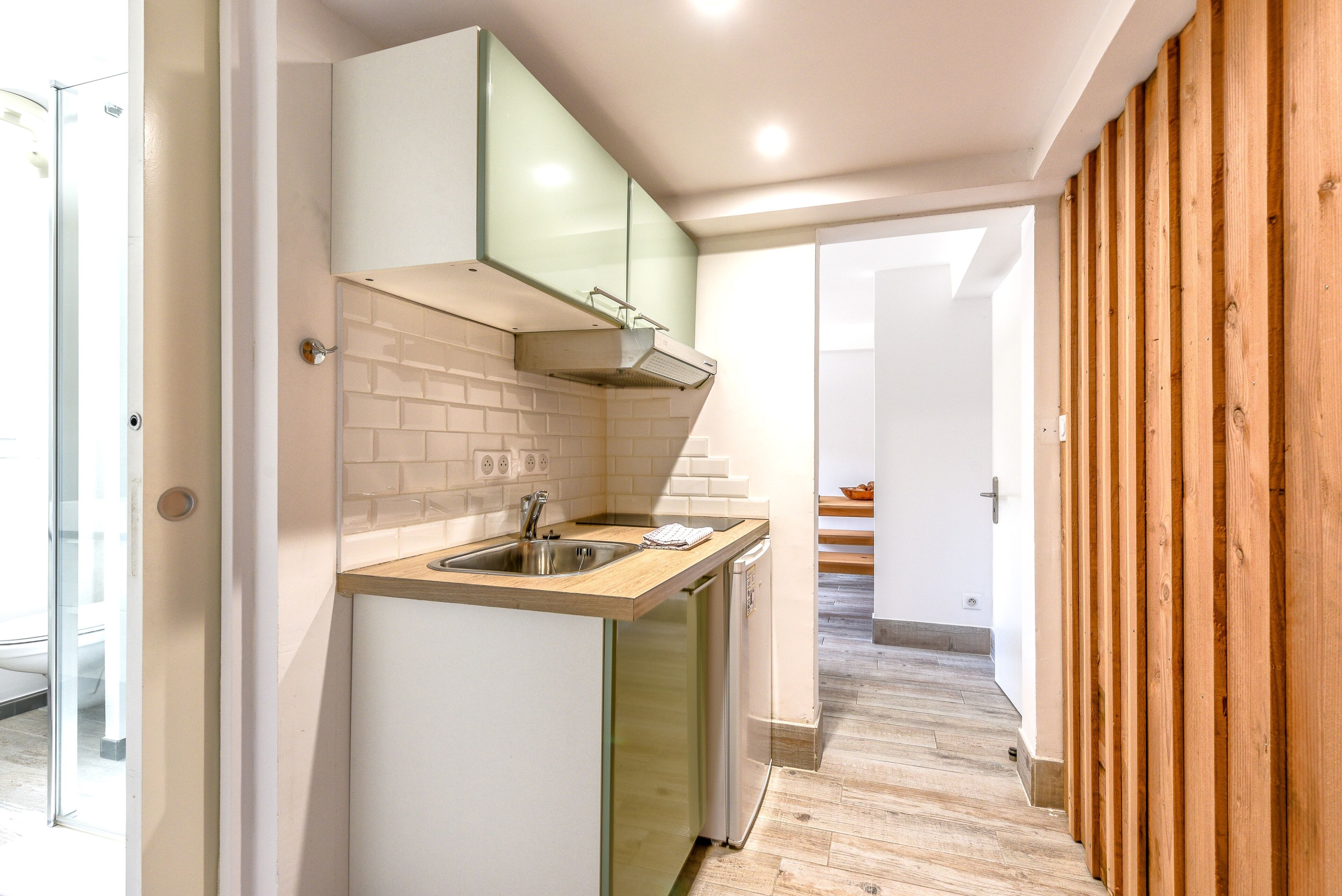 A modern kitchen with a built-in dishwasher, a stainless steel sink, and a wooden countertop.