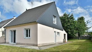 A two-story house with a sloped roof, a small front porch, and a well-maintained lawn.