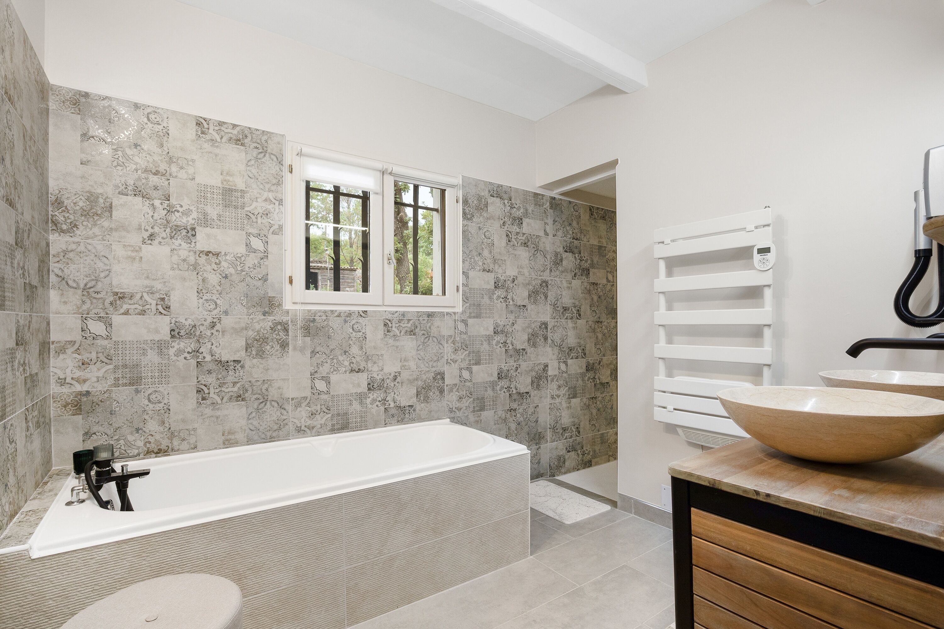 A modern bathroom with a freestanding bathtub, a large mirror, and a wooden vanity.