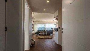 A hallway leading to a living area with a sofa, a coffee table, and a view of the outdoors.
