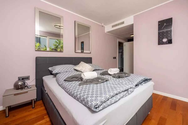 A modern bedroom with a bed, bedside table, and a wall clock.