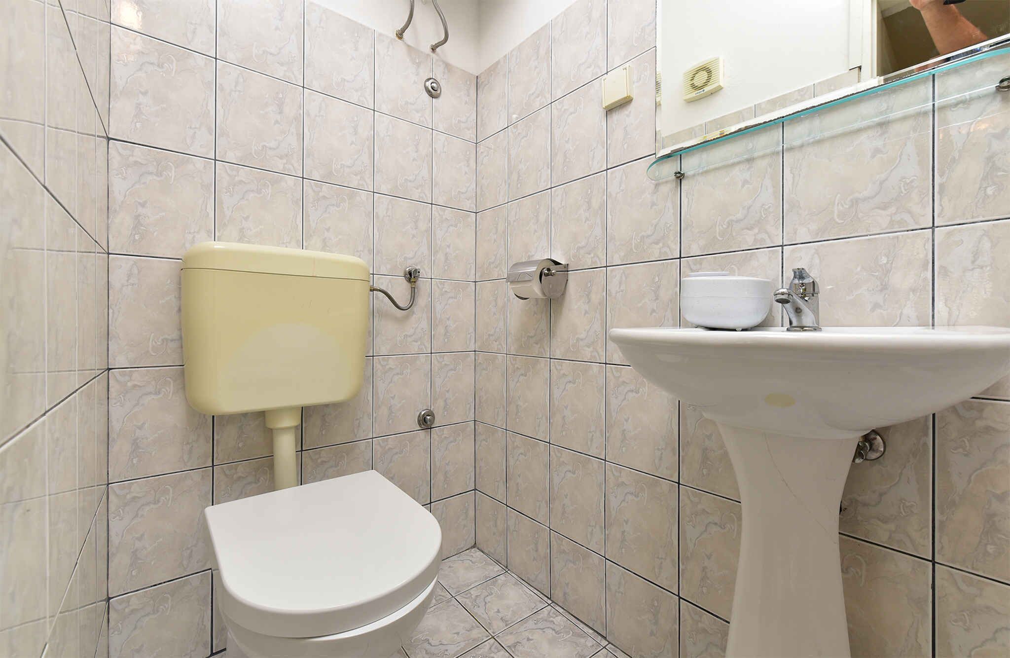 A bathroom with a toilet, sink, and mirror.