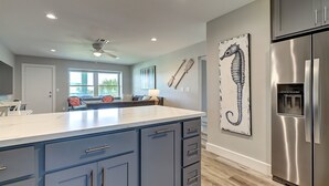 A modern kitchen with a large island, stainless steel appliances, and a seahorse artwork on the wall. - Beachfront Luxury with Gulf Views: 3BR/2BA Condo w/ Private Beach Access & Pool (Port Aransas)