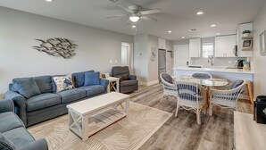 Un salon moderne comprenant un canapé, une table basse et un coin repas avec des chaises.