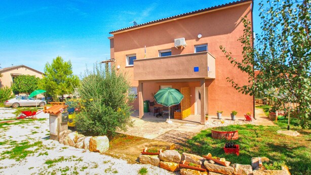 A two-story building with a flat roof, a covered outdoor seating area, and a paved driveway. - Holiday apartment with garden for shared use and children's playground (Ližnjan)