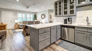 A modern kitchen with grey cabinets, a dishwasher, and a coffee maker. - Newly Remodeled 2BR Condo with Private Path to Beach, Pool View, & Close to Town (Port Aransas)