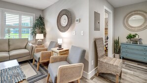 A living room with a sofa, two armchairs, a coffee table, a lamp, a potted plant, and a blue dresser. - Newly Remodeled 2BR Condo with Private Path to Beach, Pool View, & Close to Town (Port Aransas)