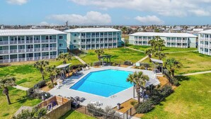 A resort with a central swimming pool, multiple buildings, and a well-maintained lawn. - Newly Remodeled 2BR Condo with Private Path to Beach, Pool View, & Close to Town (Port Aransas)