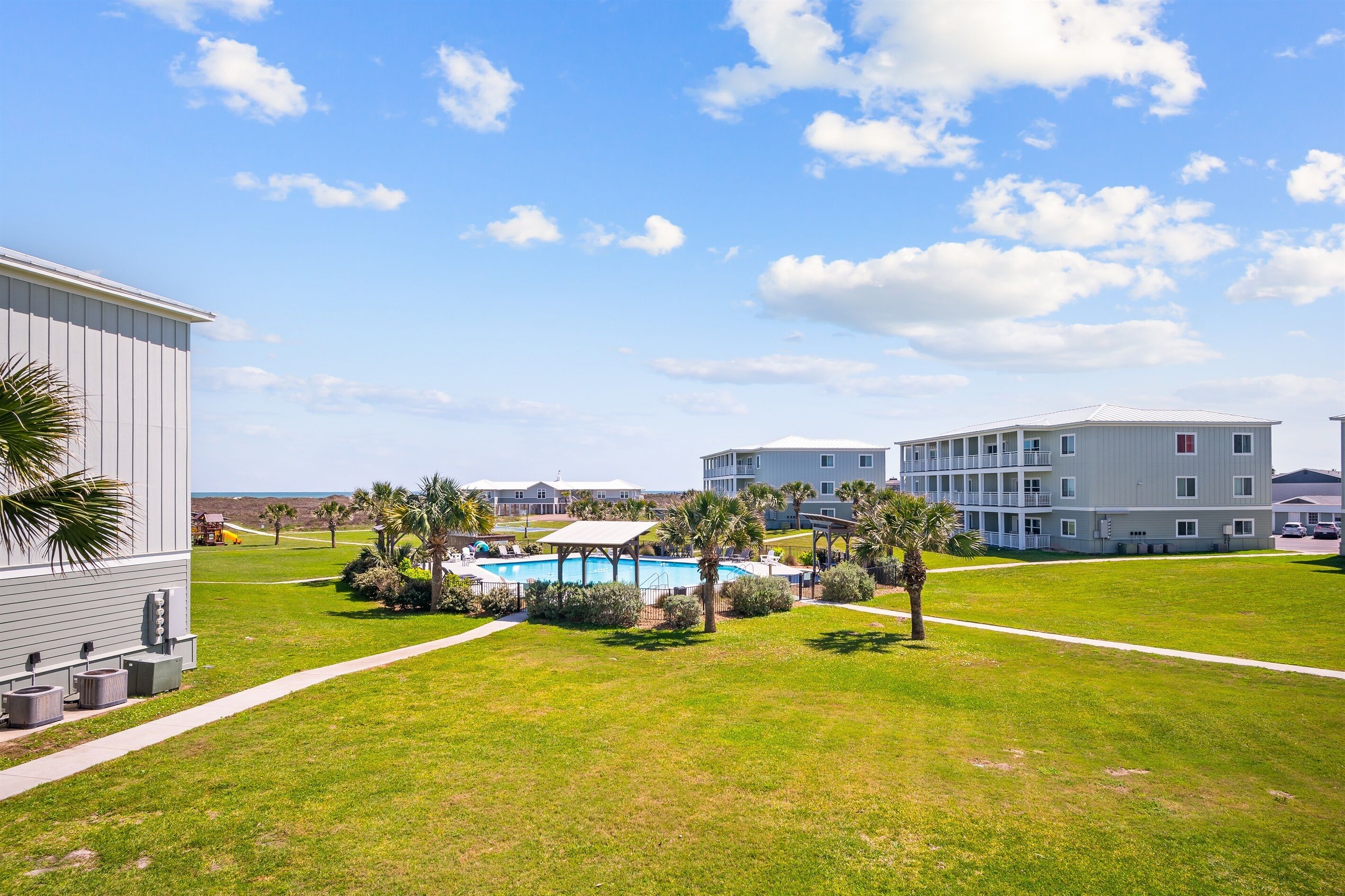 A residential area with a swimming pool, palm trees, and a large building with multiple balconies.