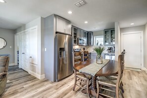 A modern kitchen with stainless steel appliances, wooden dining table, and built-in cabinets. - Relax and Unwind in this Stunning 2BR Beach Condo Close to Town & the Beach (Port Aransas)