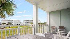 A covered outdoor area with a table and chairs, a view of other buildings, and a railing. - 3BR Condo w/ Pool View, Private Beach Access & Short Walk to Town and the Beach (Port Aransas)
