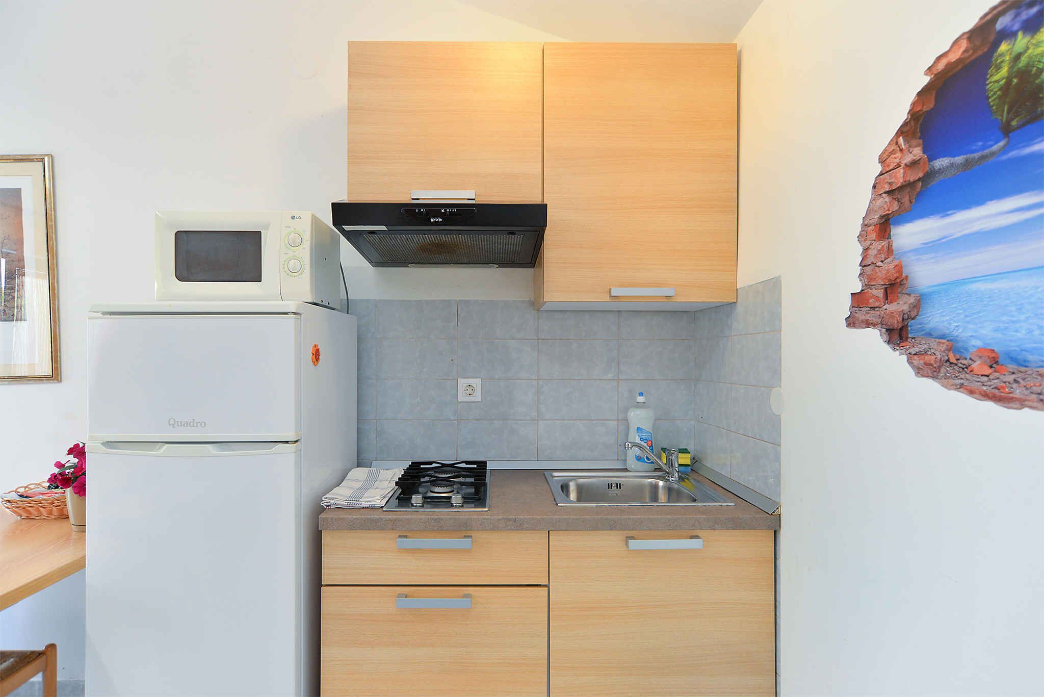 A compact kitchen with a microwave, stove, and sink.