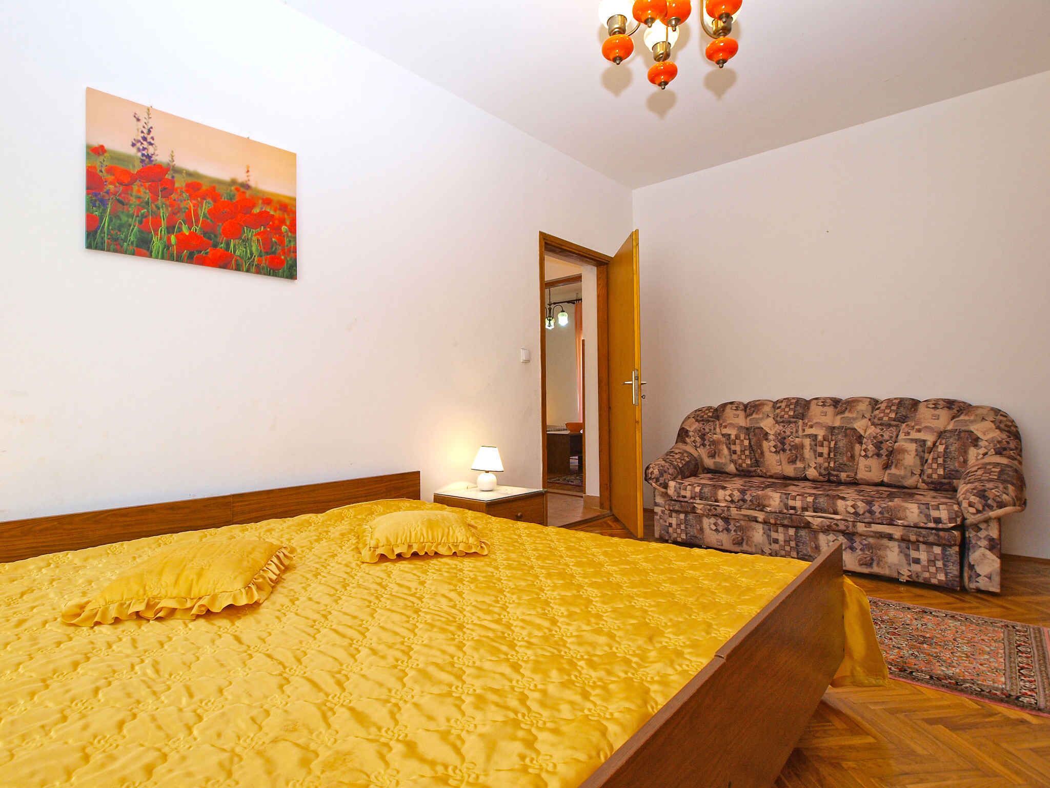 A bedroom with a bed, a patterned sofa, a painting, and a chandelier.
