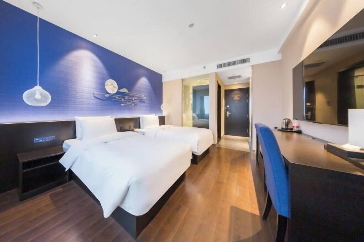 Une chambre d’hôtel moderne avec un grand lit, des tables de chevet, un bureau et un miroir.