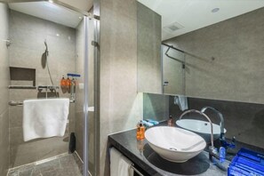 A modern bathroom with a glass shower enclosure, a white sink, and a large mirror.
