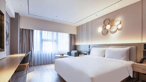 Quarto de hotel moderno com uma cama grande, uma escrivaninha e um espaço de estar.