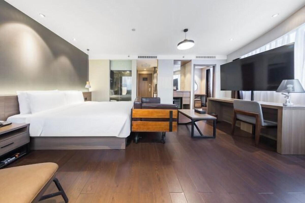 Una habitación de hotel con cama, escritorio, silla, televisor y una pequeña mesa.