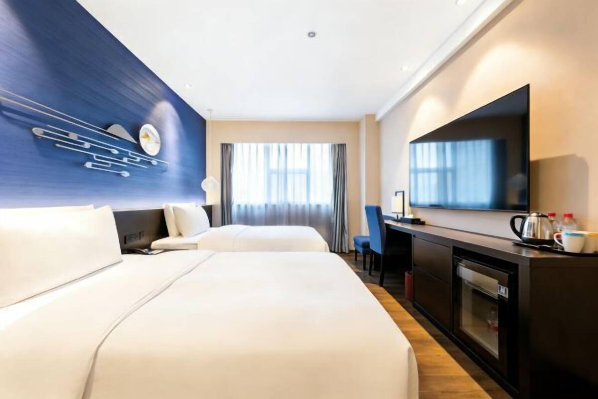 Une chambre d’hôtel avec deux lits, un téléviseur à écran plat, un bureau avec une chaise et une machine à café.