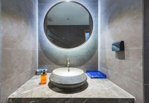Un baño con un espejo redondo, un lavabo y un dispensador de jabón.