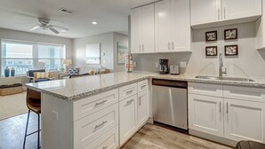A modern kitchen with white cabinets, a dishwasher, and a granite countertop.