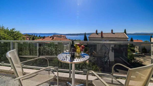 A balcony with a table and chairs, overlooking a scenic view of a body of water and distant hills. - Holiday apartment with air conditioning (Crikvenica)
