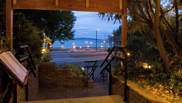 A wooden staircase leading to a covered area with a view of a road and distant mountains. - Hotel Lar Aike (El Calafate)