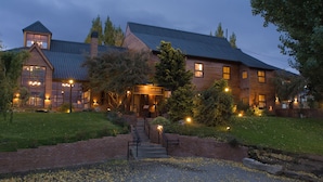 A large, rustic hotel with a prominent entrance, multiple windows, and a well-lit exterior. - Hotel Lar Aike (El Calafate)
