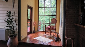 A wooden deck with a rocking chair and a potted plant. - Hotel Lar Aike (El Calafate)