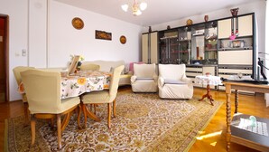 Un rincón de comedor con una mesa y sillas, un sofá, un mueble espejo y una alfombra estampada.