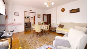 Una sala de estar con una mesa de comedor, sillas, un sofá y un televisor.