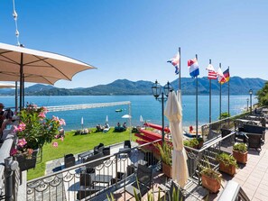 A terrace with outdoor seating, a view of the lake, and flags. - Holiday apartment with TV and heating (Oggebbio)