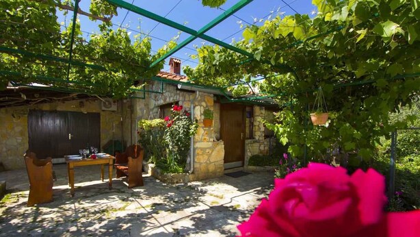 A stone building with a covered patio, a table with chairs, and a hanging flower pot. - with swimming pool and garden for exclusive use (Valbandon)