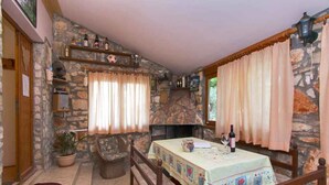 A rustic room with stone walls, a fireplace, a dining table with a tablecloth, and a bench. - with swimming pool and garden for exclusive use (Valbandon)