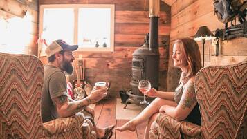 A cozy cabin interior with wooden walls, a fireplace, and two upholstered chairs facing each other.