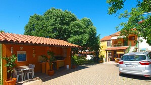 A courtyard with a paved walkway, outdoor seating, and a parked car. - Holiday apartment with garden and barbecue (Pomer)
