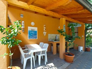 Eine Terrasse im Freien mit Holzboden, einem Tisch mit Stühlen und Blumentöpfen.