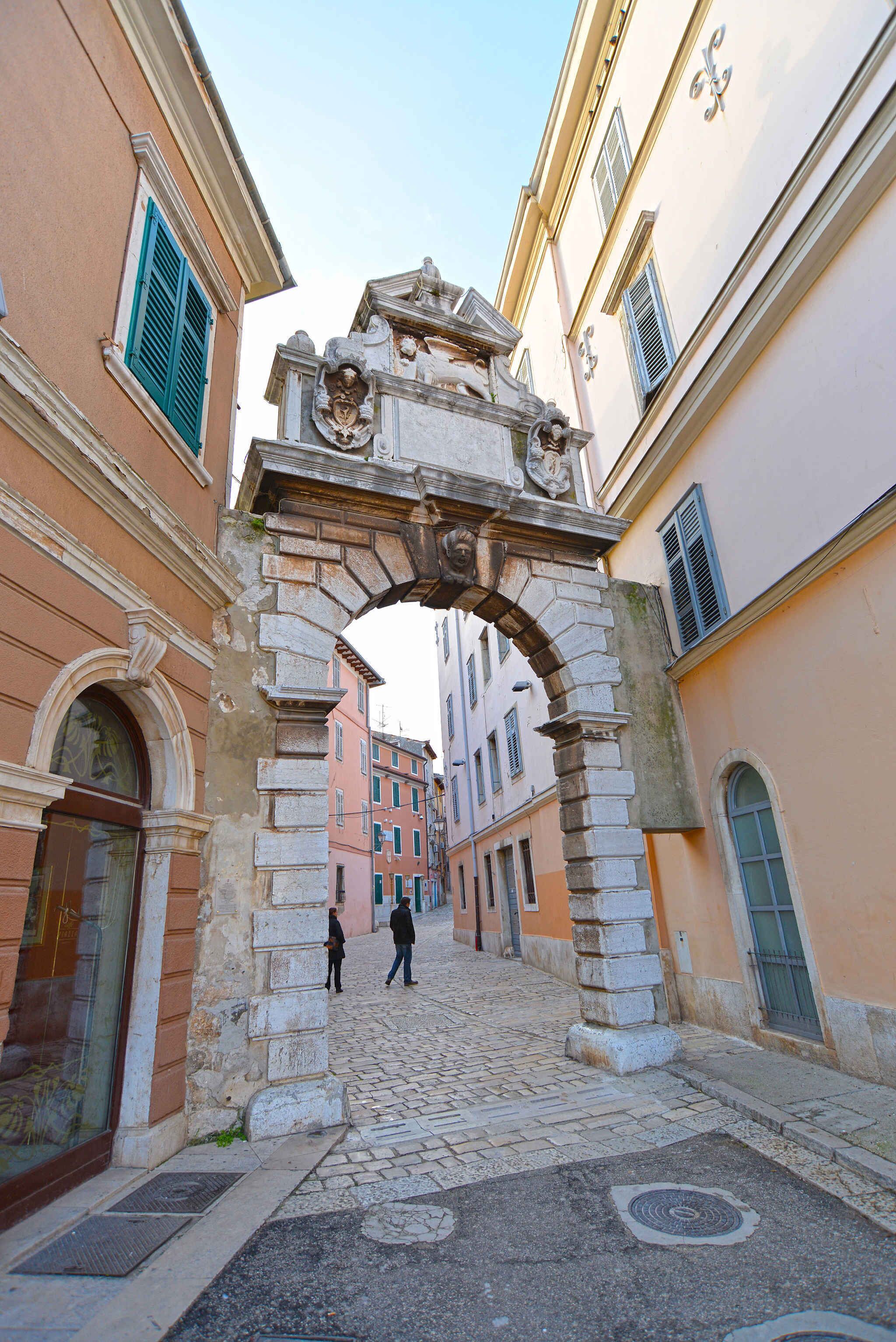 A cobblestone street with an ornate stone archway.