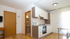A compact kitchen with a wooden floor, a built-in oven, and a coffee maker. - Holiday apartment with pool and barbecue (Novigrad)