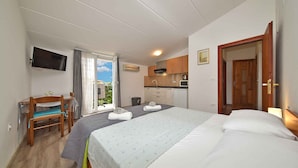 A hotel room with a bed, a desk, a television, and a kitchenette.