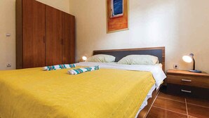 Un dormitorio con cama, armario de madera, mesitas de noche y un cuadro en la pared.