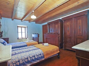 A bedroom with two beds, wooden wardrobe, and a window.