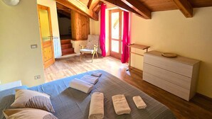 A bedroom with a wooden ceiling, a bed with towels, a dresser, and a chair.