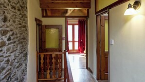 A wooden staircase leading to a second floor with a stone wall on one side and a wooden railing.
