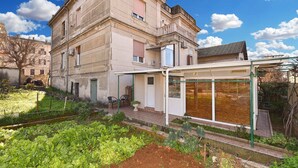 Un bâtiment doté d’un jardin, d’un espace extérieur abrité avec des sièges et d’une grande fenêtre.