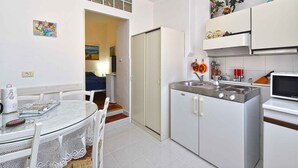 Une cuisine compacte comprenant une table à manger, des chaises, un réfrigérateur, un four à micro-ondes et une cuisinière.